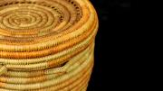A round, yellow and orange, coiled basket with a lid but no handle. 